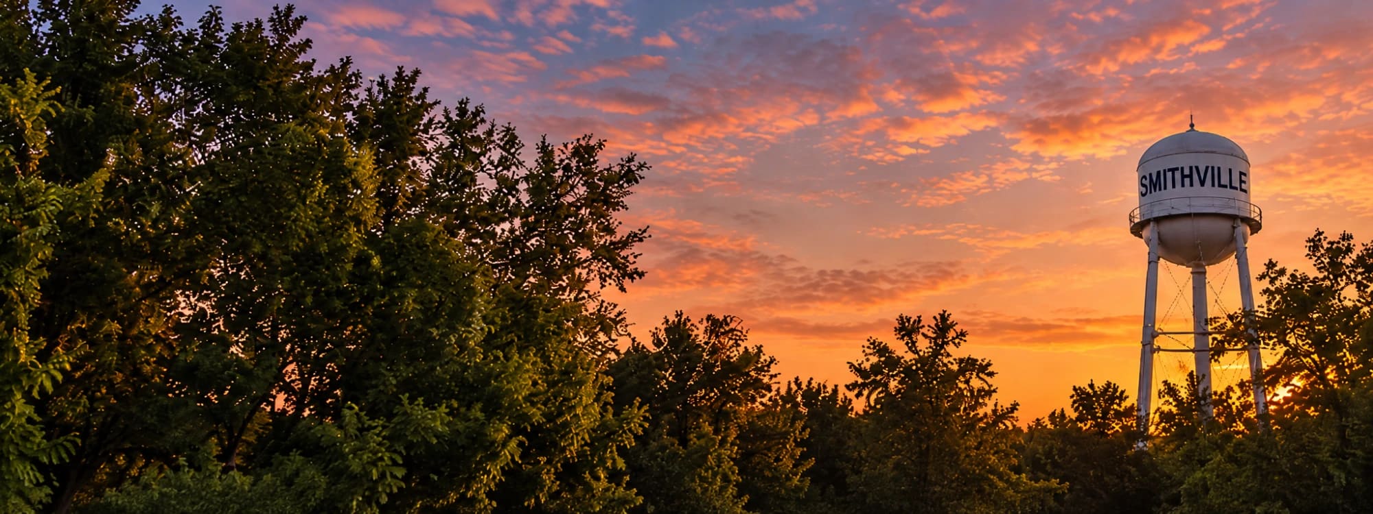 The Smithville water tower at sunset above the trees